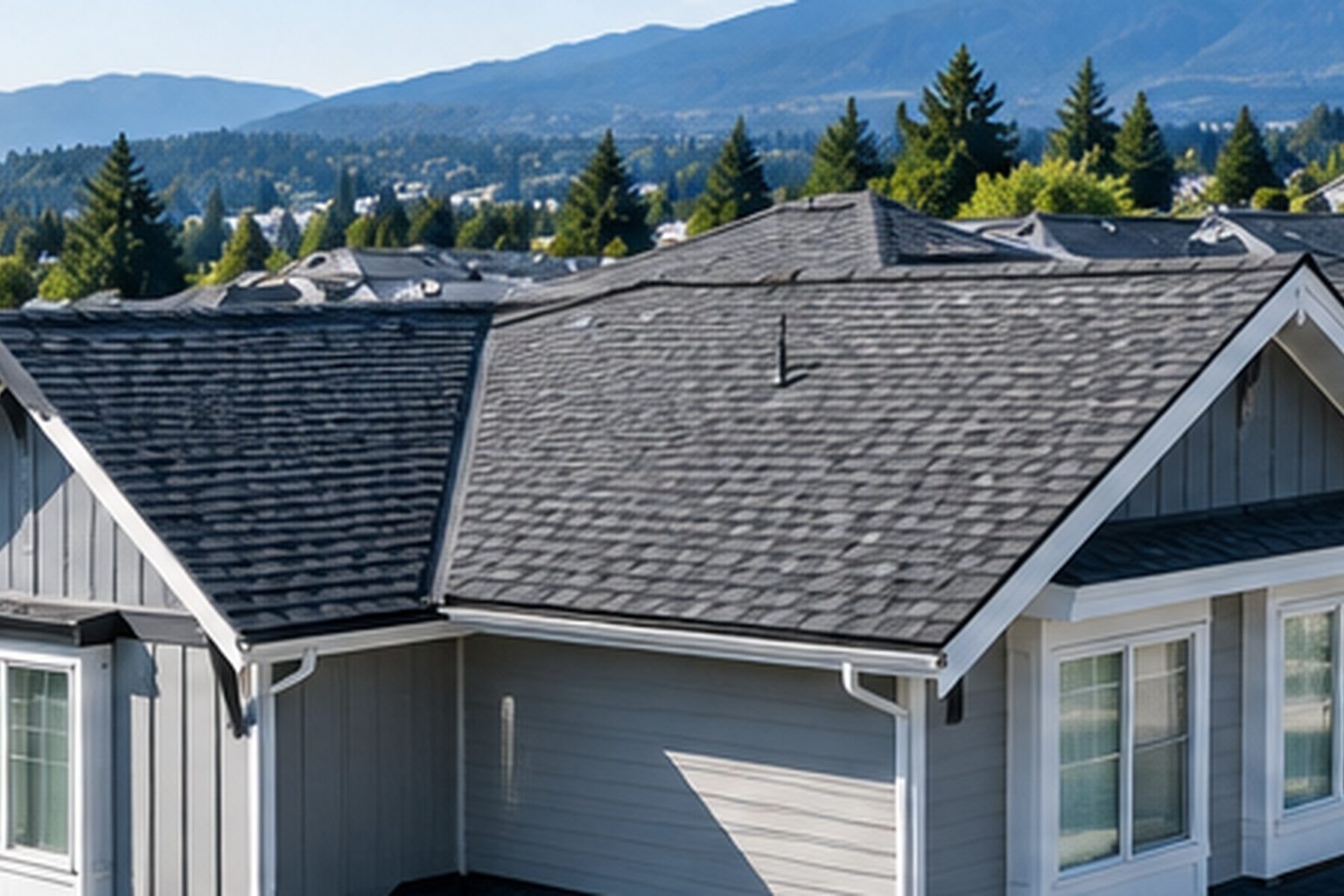 Row of townhouse roofs with asphalt shingles, mountains in the distance