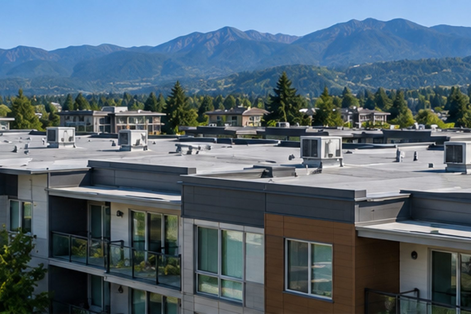 Condominium buildings with flat roofs and rooftop units, mountains in the distance