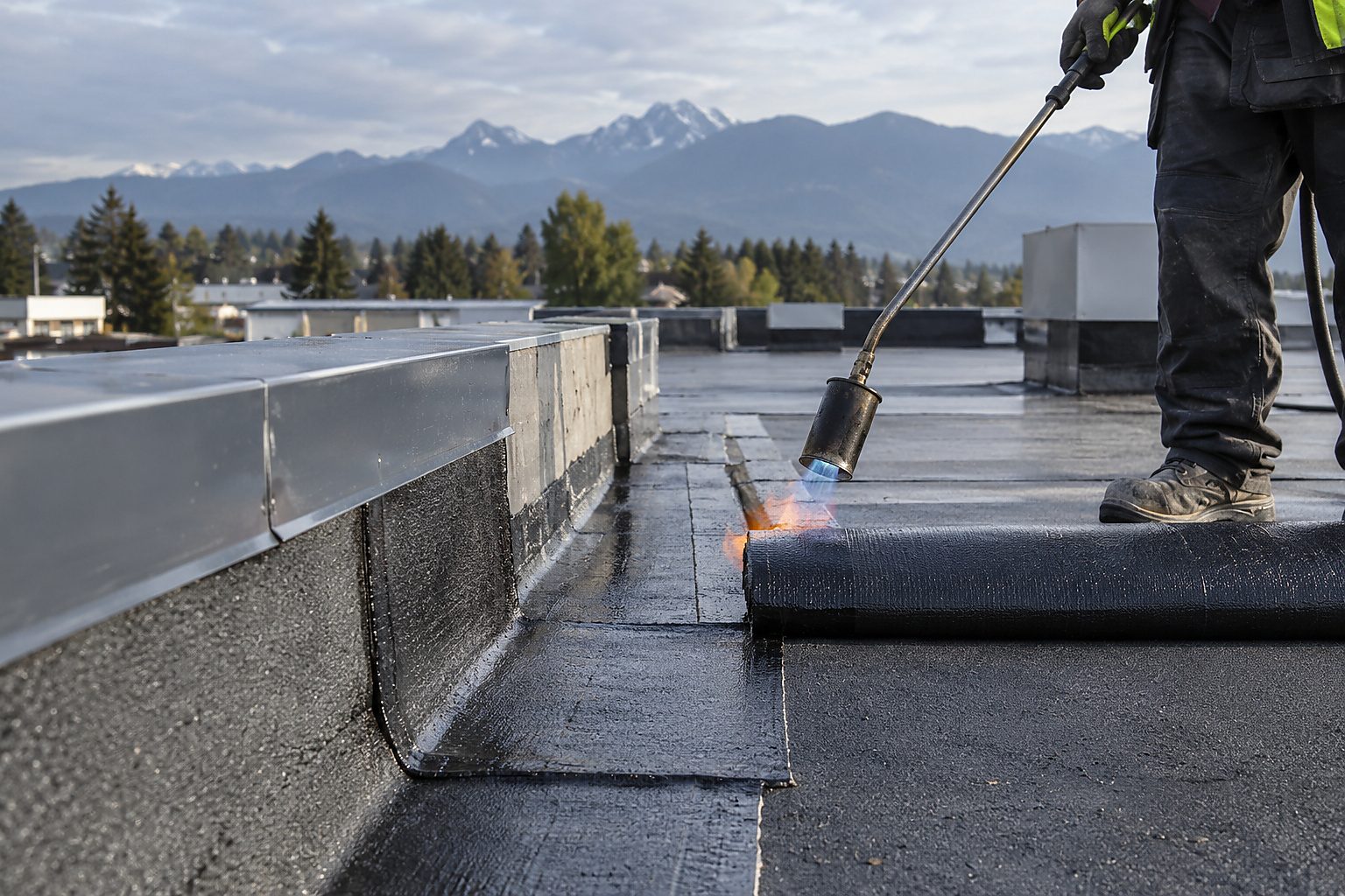 Commercial roofing crew installing modified-bitumen membrane on a low-slope roof